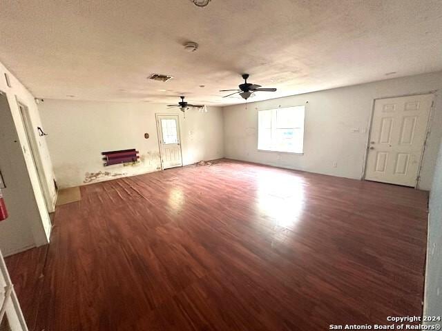 unfurnished room featuring a textured ceiling, ceiling fan, and dark wood-type flooring