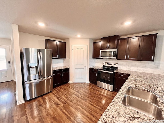 kitchen with dark brown cabinetry, stainless steel appliances, dark hardwood / wood-style floors, and sink