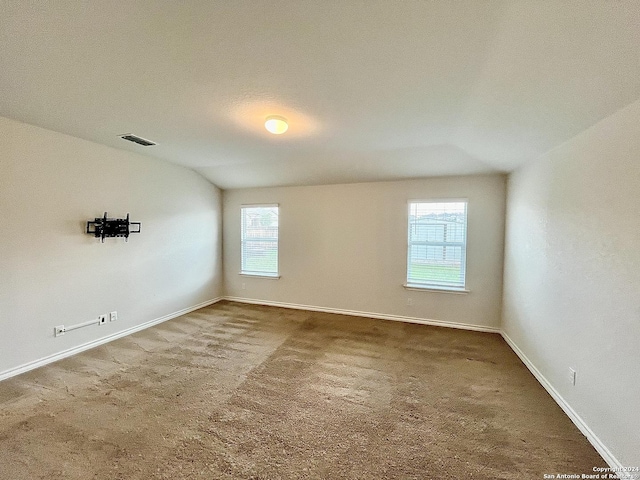 spare room featuring carpet, a textured ceiling, and vaulted ceiling