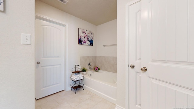 bathroom with tile patterned flooring, a bathtub, and a textured ceiling