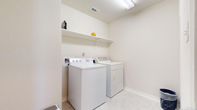 laundry area with washer and clothes dryer, light tile patterned flooring, and a textured ceiling