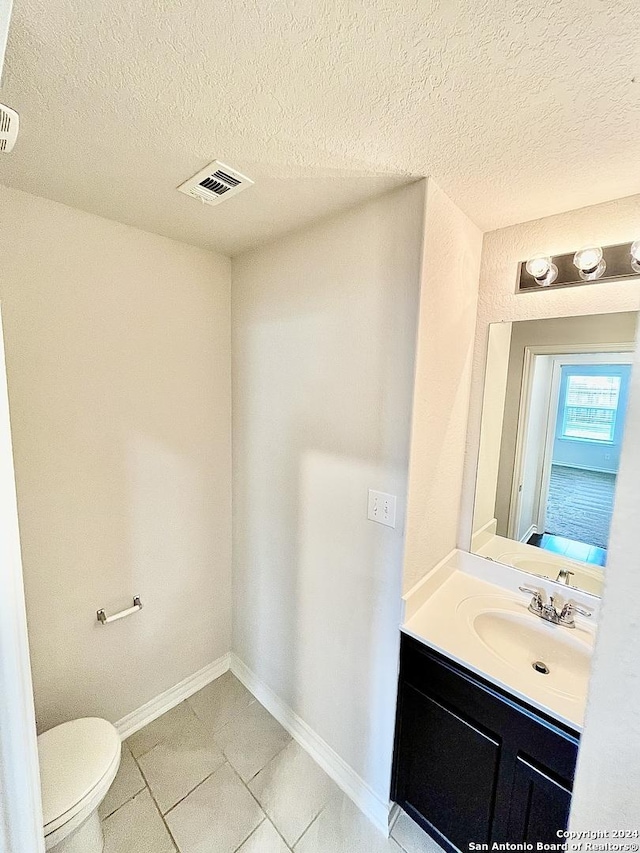 bathroom with tile patterned flooring, vanity, toilet, and a textured ceiling