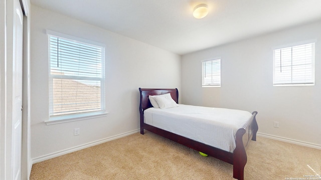 bedroom with light colored carpet and multiple windows