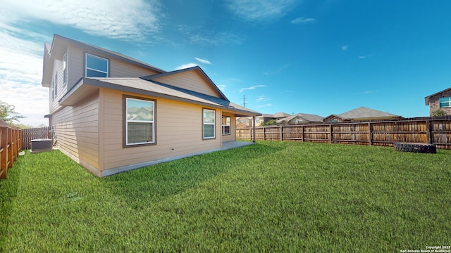 rear view of house with central AC unit and a lawn