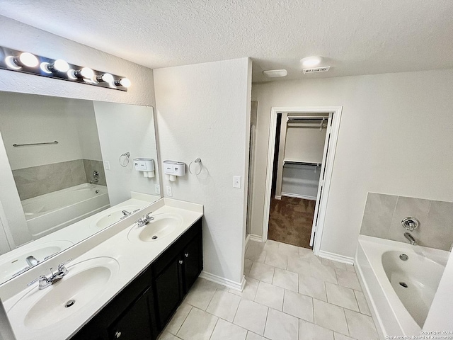 bathroom featuring vanity, a bath, a textured ceiling, and tile patterned floors