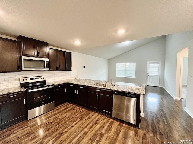 kitchen featuring lofted ceiling, sink, kitchen peninsula, wood-type flooring, and stainless steel appliances