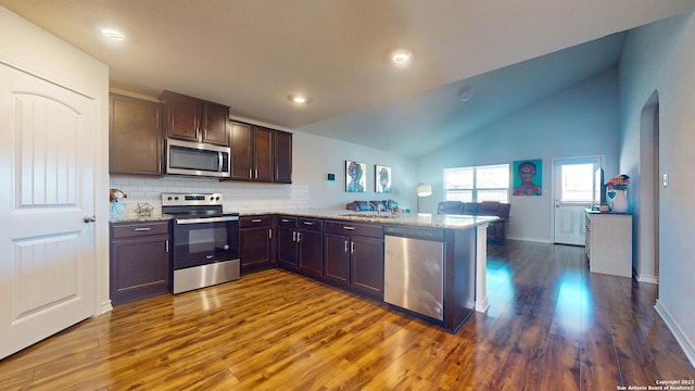 kitchen with kitchen peninsula, light stone counters, dark wood-type flooring, and appliances with stainless steel finishes