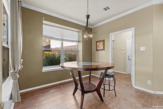 dining room featuring hardwood / wood-style flooring, crown molding, and an inviting chandelier