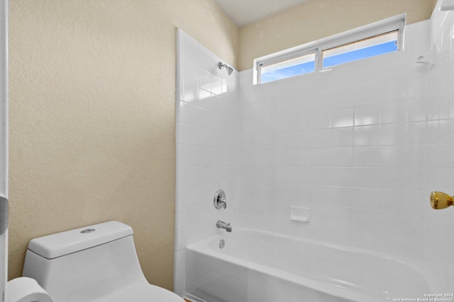 bathroom featuring tiled shower / bath combo and toilet