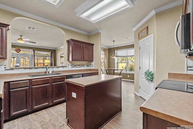 kitchen with crown molding, sink, light hardwood / wood-style flooring, a kitchen island, and hanging light fixtures