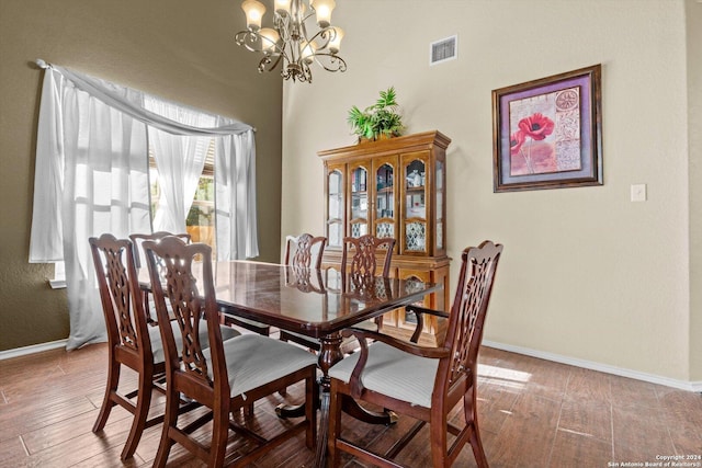 dining space with wood-type flooring and an inviting chandelier