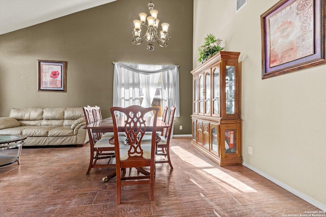 dining space featuring hardwood / wood-style floors, a notable chandelier, and high vaulted ceiling