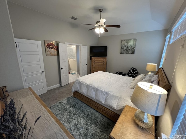 bedroom with ceiling fan, carpet, ensuite bathroom, and vaulted ceiling