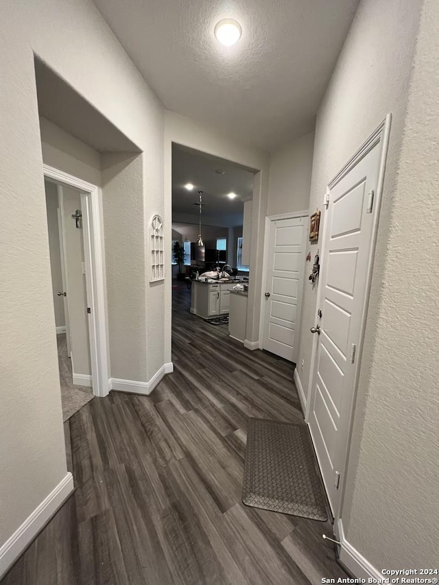 corridor with a textured ceiling and dark hardwood / wood-style floors