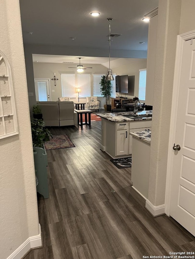 kitchen with pendant lighting, dark hardwood / wood-style floors, ceiling fan, light stone counters, and white cabinetry