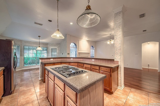 kitchen with ceiling fan, hanging light fixtures, stainless steel appliances, light hardwood / wood-style flooring, and a kitchen island