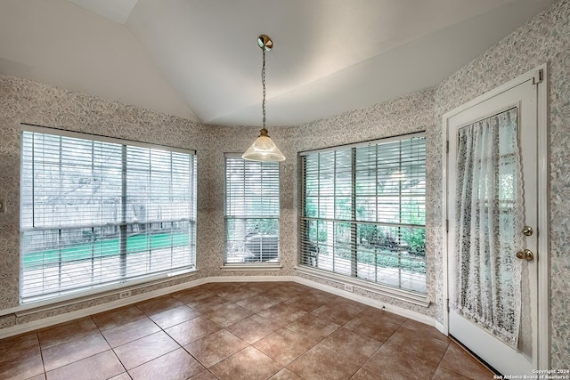 unfurnished dining area featuring a healthy amount of sunlight, tile patterned floors, and lofted ceiling