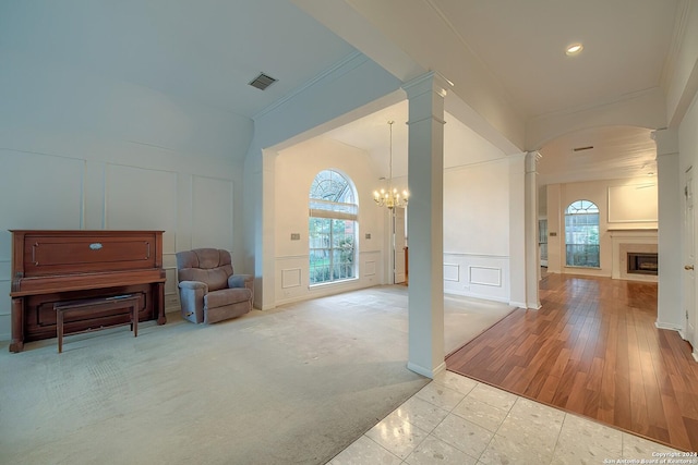 interior space with decorative columns, crown molding, light hardwood / wood-style floors, and a notable chandelier