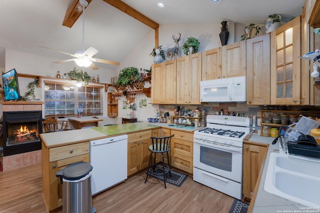 kitchen featuring sink, vaulted ceiling with beams, light hardwood / wood-style flooring, white appliances, and a tiled fireplace