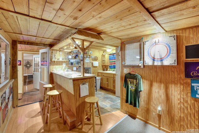 kitchen with light hardwood / wood-style floors, wood walls, light stone counters, and wood ceiling