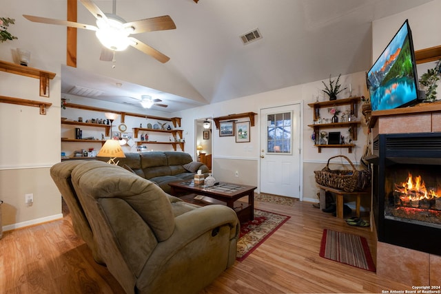 living room featuring a tile fireplace, light wood-type flooring, and high vaulted ceiling