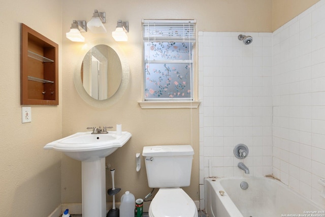 bathroom with built in shelves, tiled shower / bath combo, and toilet