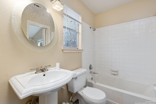 full bathroom featuring tiled shower / bath combo, toilet, and sink