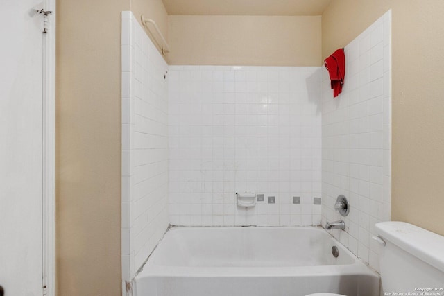 bathroom with tiled shower / bath combo and toilet