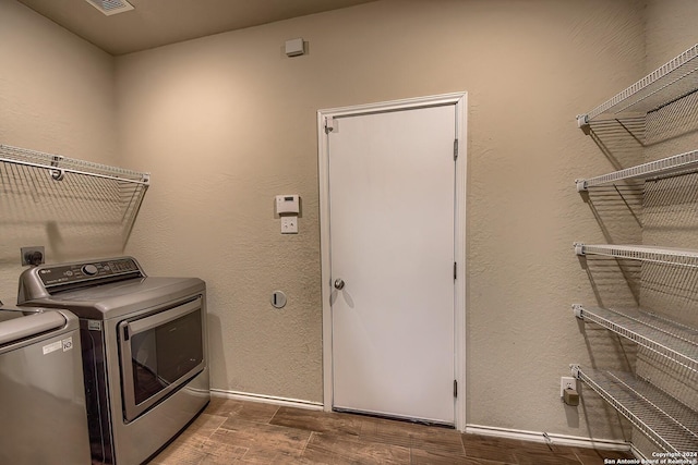 clothes washing area with washing machine and clothes dryer and wood-type flooring