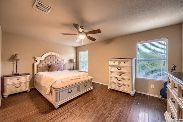 bedroom with multiple windows, ceiling fan, dark wood-type flooring, and a textured ceiling