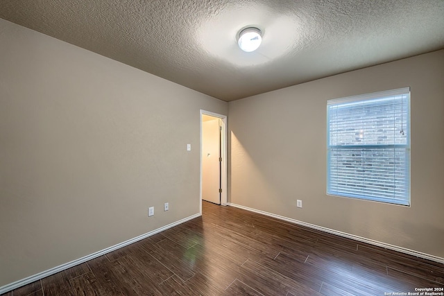 unfurnished room with dark hardwood / wood-style floors and a textured ceiling