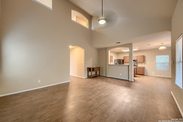 unfurnished living room with ceiling fan, dark hardwood / wood-style flooring, and high vaulted ceiling