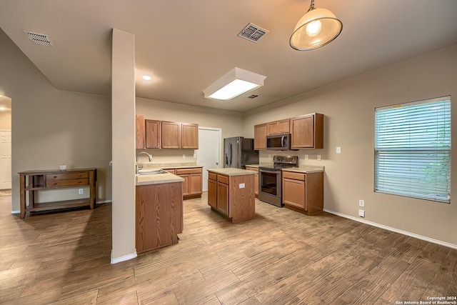 kitchen with appliances with stainless steel finishes, a center island, light hardwood / wood-style floors, and sink