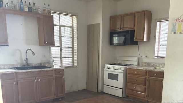 kitchen featuring a wealth of natural light, white gas range, and sink