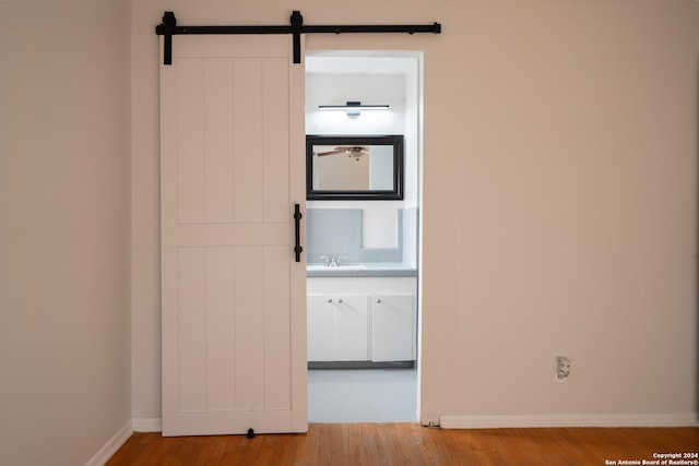 hall with a barn door, sink, and hardwood / wood-style flooring