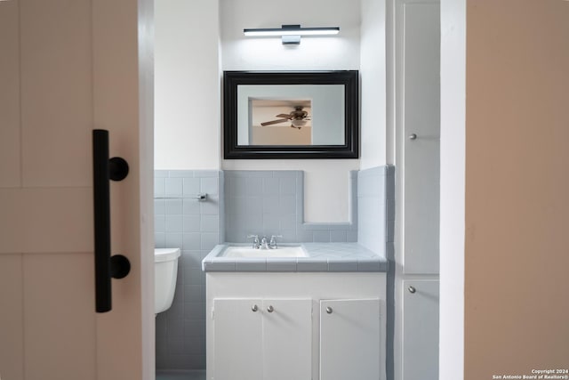 bathroom with vanity, tile walls, and toilet