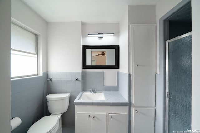 bathroom featuring vanity, toilet, and tile walls