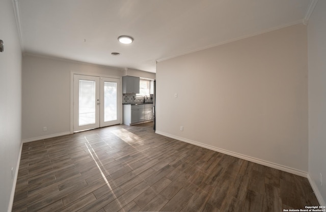 empty room featuring french doors, crown molding, dark wood-type flooring, and sink