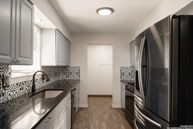 kitchen featuring sink, dark stone countertops, gray cabinets, appliances with stainless steel finishes, and light wood-type flooring