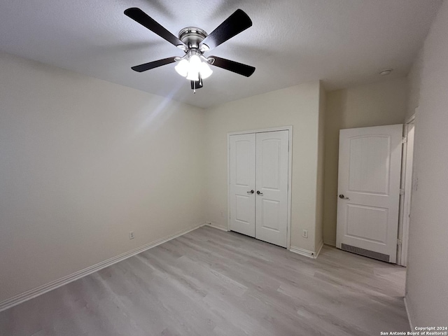 unfurnished bedroom featuring ceiling fan, a closet, a textured ceiling, and light hardwood / wood-style flooring