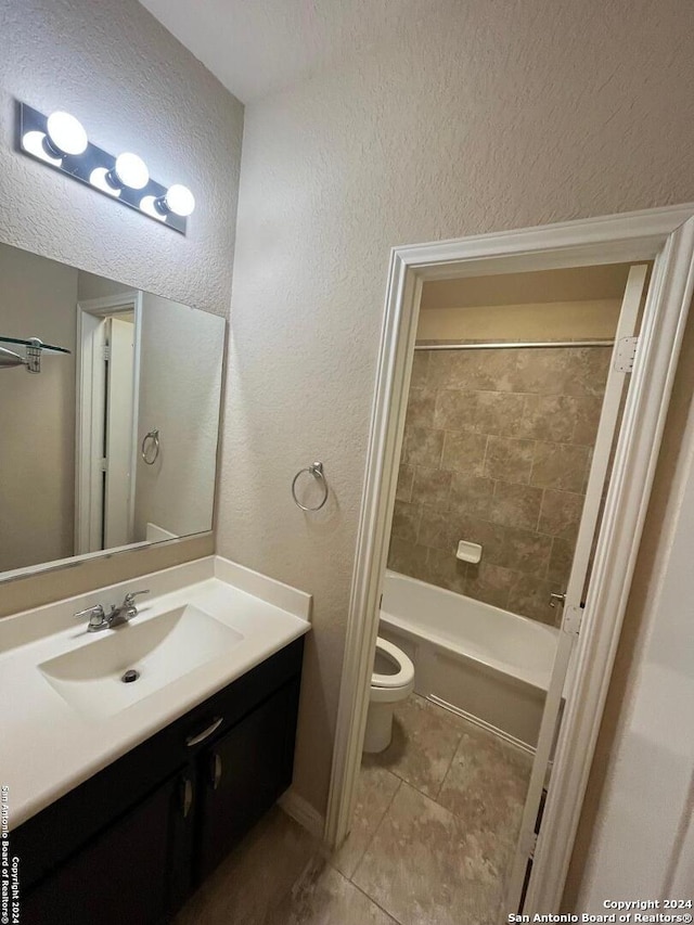 full bathroom with tile patterned flooring, vanity, tiled shower / bath combo, and toilet