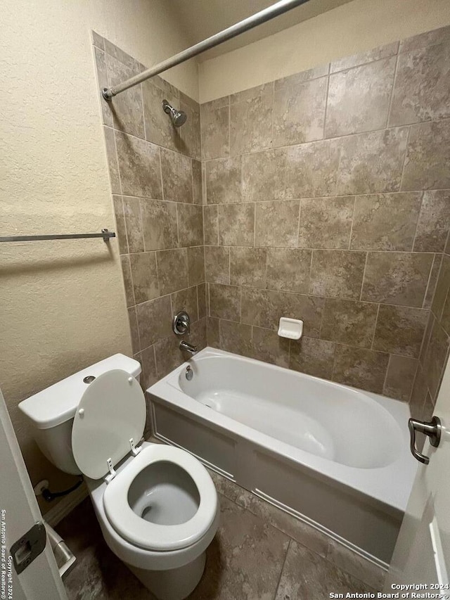 bathroom with tiled shower / bath combo and toilet