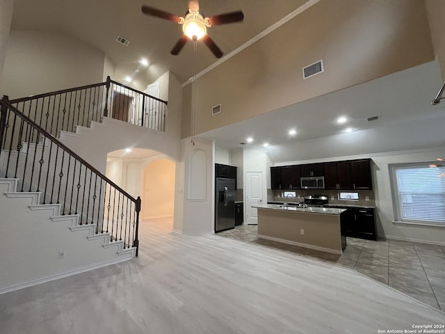 kitchen with ceiling fan, a kitchen island, ornamental molding, and stainless steel appliances