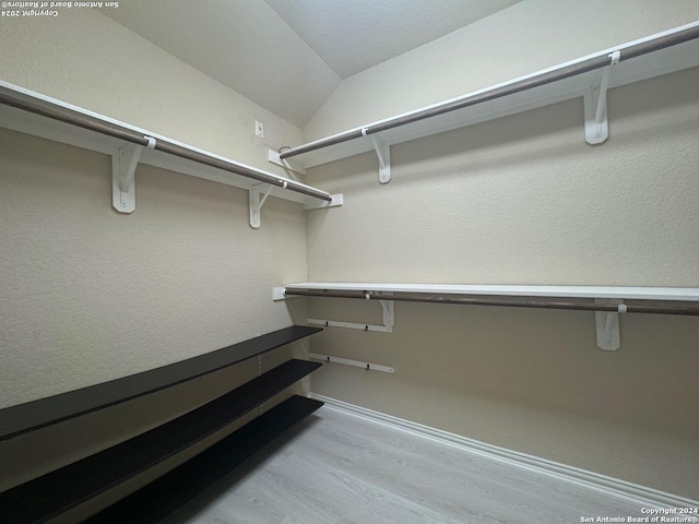 spacious closet featuring light wood-type flooring and vaulted ceiling