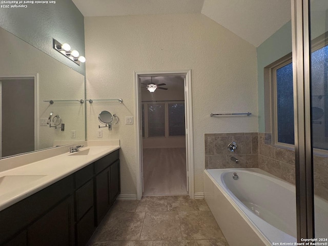 bathroom with ceiling fan, lofted ceiling, a tub to relax in, and vanity