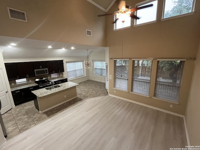 kitchen featuring sink, pendant lighting, a center island with sink, ceiling fan with notable chandelier, and appliances with stainless steel finishes