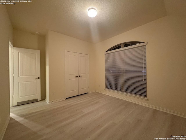 unfurnished bedroom with a closet, a textured ceiling, and light hardwood / wood-style flooring