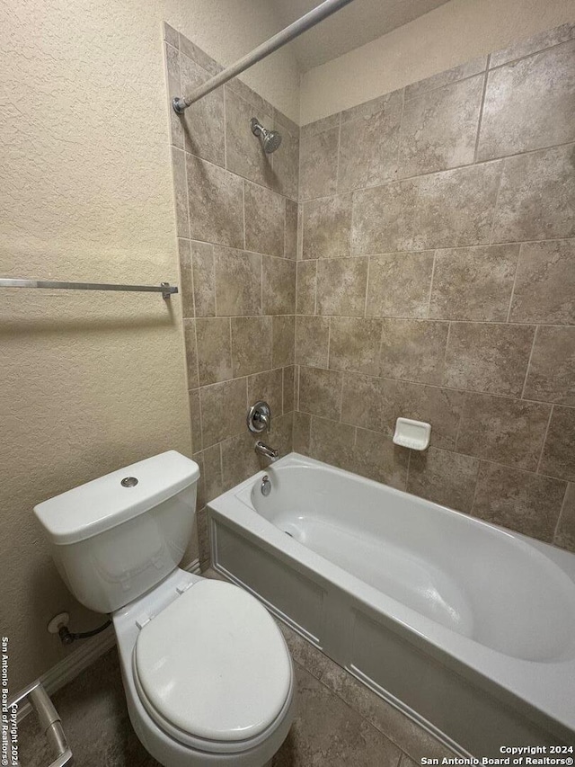 bathroom with toilet and tiled shower / bath