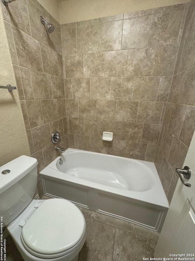 bathroom featuring tile patterned flooring, toilet, and tiled shower / bath