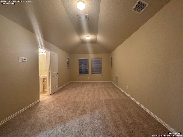 carpeted spare room featuring a textured ceiling and lofted ceiling